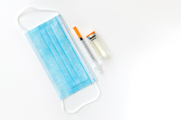 Vaccine vial, syringes and surgical mask isolated on white background, flat lay with space for text. Vaccination and immunization