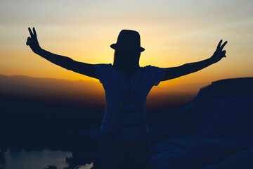 Silhouette of two fingers of woman hand or victory in front of the sun during sunset time. Fighting concept