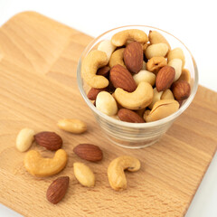 Mix nuts in circle shaped glass bowls on wooden Butcher isolated on white background. Almonds, macadamia, cashew, peanuts for healthy ingredients food concept.