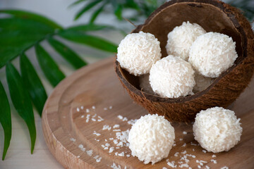 Homemade white chocolate candies in coconut flakes in nut shell on wooden background. Easy recipe...