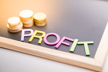 Profit text on blackboard with coin and light