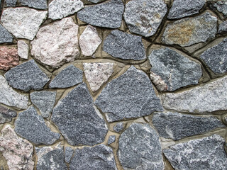 Smooth gray stones embedded in the wall. Cobblestone cover.