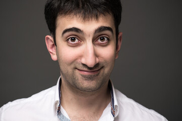 Portrait of caucasian man with brown eyes expressing positive emotions in studio, with grey background