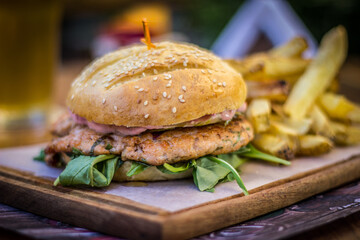 Salmon gourmet Burger Patty with chips and beer on a wood plank and wooden table