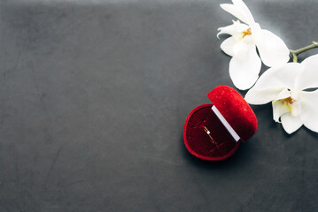 Gold wedding ring in a red box with a diamond on a black stone background. surprise for valentine's day