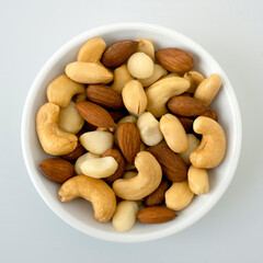 Nuts in top view circle shaped ceramic bowls isolated on gray background. Various nuts (almonds, macadamia, cashew, peanuts). Mix nut healthy ingredients food.