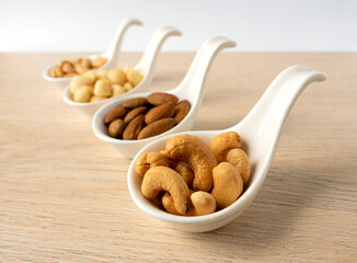 Organic cashew nuts, almond nuts and macadamia nuts and peanut  in ceramic spoon shape cup on wooden table. Mix nut healthy ingredients food.