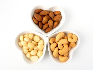 Nuts in Heart shaped bowls top view isolated on white background. Various nuts (almonds, macadamia, cashew). Mix nut for romantic feelings and healthy ingredients food.