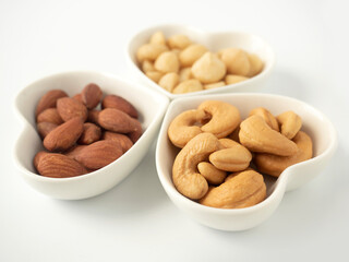 Nuts in Heart shaped bowls isolated on white background. Various nuts (almonds, macadamia, cashew). Mix nut for romantic feelings and healthy ingredients food.