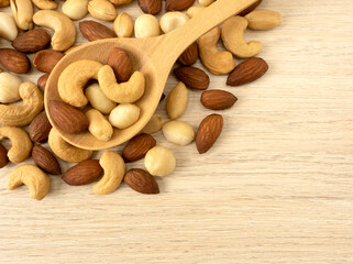 Organic cashew nuts, almond nuts and macadamia nuts and peanut  in wooden spoon on wooden table with copy space. Mix nut healthy ingredients food.