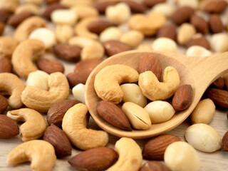 Organic cashew nuts, almond nuts and macadamia nuts and peanut  in wooden spoon on wooden table. Mix nut healthy ingredients food.