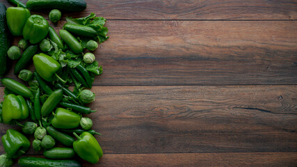 Food background. Bell green peppers, cucumbers, hot green chili peppers, brussels sprouts, green salad on wooden table.