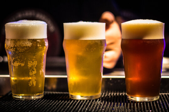 Three pints of tap beer lager, blonde and amber on in a bar with bartender