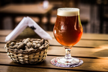 Barley wine beer glass with peanuts on a wooden table