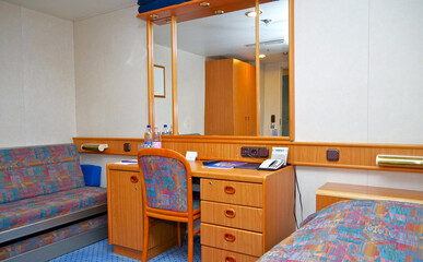 Cozy but dated cabin or stateroom on classic cruiseship or cruise ship liner with desk, bed, chair...