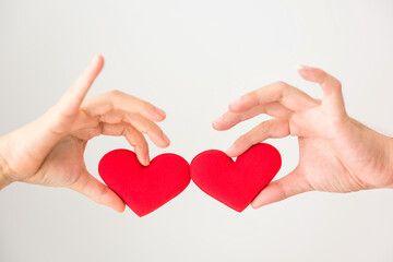 Couple hands hold and bump red fake heart