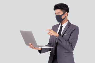 Young asian business man in face mask using laptop computer isolated on white background, quarantine and epidemic covid-19, businessman work from home for health, social distancing, new normal.