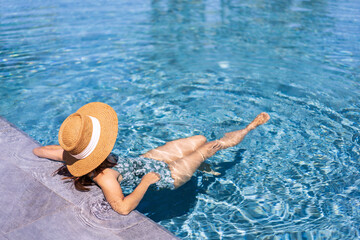 Young woman traveler relaxing and enjoying by a tropical resort pool while traveling for summer vacation, Travel concept