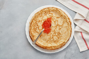 Crepes, thin pancakes, Russian pancakes with red caviar on gray plate. Marble background. Copy space. Top view.
