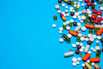 Antiviral capsules, tablets for treatment lie on a blue background. multi-colored capsules. wad health care concept from top