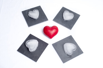 Top view on a red love heart and 4 slate plates with ice hearts on them, on a white background