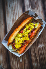 Philly cheese steak sandwich with meat, vegetables, cheese and sause in box on wooden table. street food