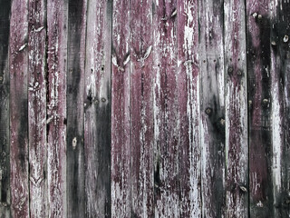 Old burgundy fence with black scuffs. Stock photo of an ancient fence of a house.
