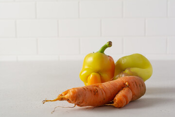 Two ugly peppers and carrots that looks like a strange face on a light table. Funny, unnormal...