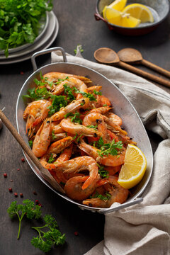 Roasted shrimps with garlic, lemon and parsley, black background, top view, copy space.