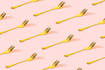 Pattern made of gold fork with nice pastel pink background. Minimal celebration party concept art
