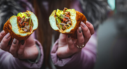 woman hand hold cut Philly cheese steak sandwich with meat, vegetables, cheese and sause