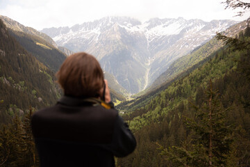 Naklejka premium Man photographing beautiful mountainous landscape with valley and forests