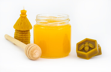 Jar of honey, wax, candle and wooden dipper