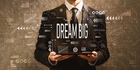 Dream big with businessman holding a tablet computer on a dark vintage background