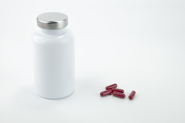Pills bottle with red pills isolated on white background.