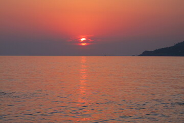 Seascape sunset on the sea, the sun is covered with clouds, the sea and the sky are pink, sun reflections on the water surface