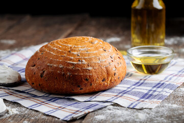 Side view on loaf of rustic bread with olive oil on the wooden table