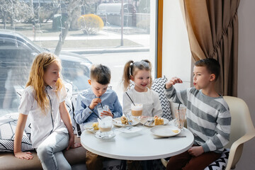 A large friendly company of children celebrate the holiday in a cafe with a delicious dessert. The...