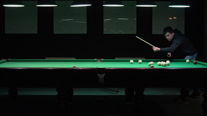 The man plays Russian billiards and pockets the ball.
