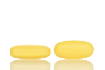Two oval yellow pills, close-up, isolated on white.