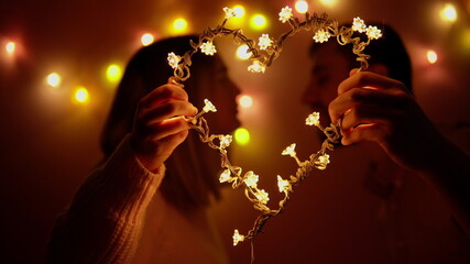 A loving couple man and woman kiss each other on Valentine's Day. Couple holding a luminous heart in their hands