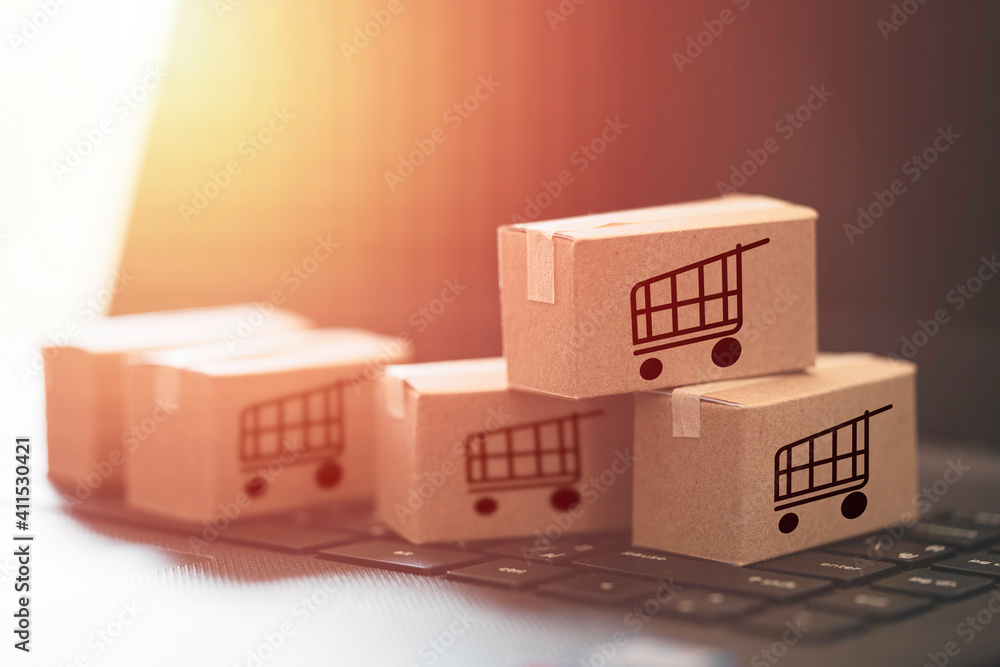 Poster trolley or shopping cart logo on small cartons boxes lay on keyboard computer laptop for online shop