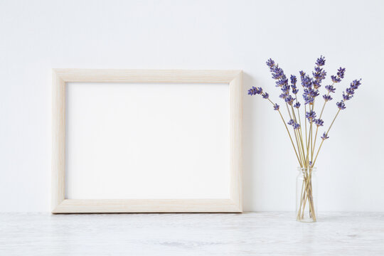 Dried purple lavender in glass vase on shelf at light gray wall background. Empty place for inspirational, emotional, sentimental text, quote, sayings or photo in white frame. Front view. Closeup.