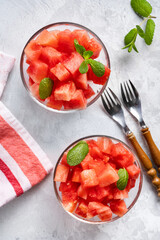 Top view of juicy watermelon pieces in two glass bowls on light backround. Summer raw vegan food enriched with vitamins and microelements