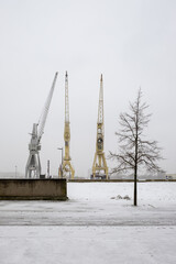 Old harbour cranes in the city of Antwerp covered in snow.
