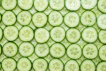 Fresh green slices of cucumber as background.