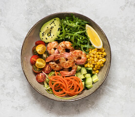Buddha bowl salad with grilled prawns, arugula, avocado, corn, tomatoes and cucumbers. Сlean eating, top view. Healhty lunch bowl. Balanced food concept.