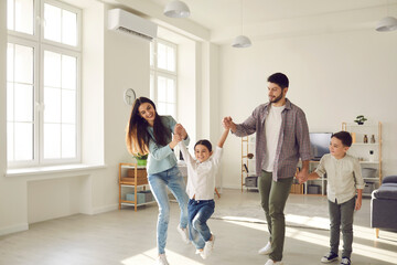 Obraz premium Smiling young parents and cheerful kids daughter and son having fun together at home on weekend with light spacious room interior at backgroundFamily spending happy time at home with children concept