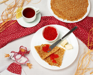 Pancakes with red caviar on the white plate. Staple of yeast pancakes, traditional for Russian pancake week. Shrovetide or Maslenitsa. Close up top view