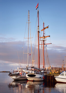 Sailboats moored to a pier in a yacht marina, close-up. A view of the shore of a small town Port Ellen at sunrise. Isle of Islay, Inner Hebrides, Scotland, UK. Sailing, cruise, recreation, tourism